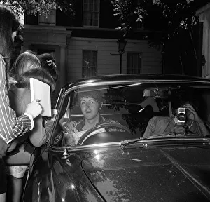 Paul McCartney sitting in his car outside his home surrounded by fans on his 25th