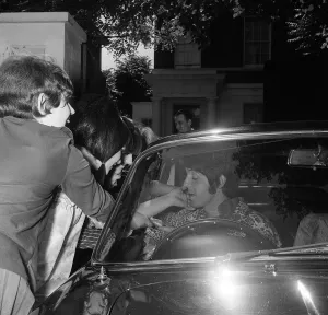 Paul McCartney sitting in his car outside his home surrounded by fans on his 25th