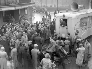People gather around the Ministry of Information van parked outside the Coventry