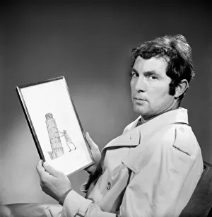 00032 Prints: People Men Humour. A man wearing an overcoat holding a framed picture of the leaning