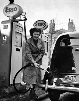 Petrol pump attendant filling up a car at an Esso service station. January 1953