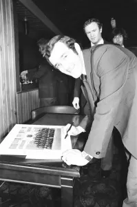 00414 Prints: Phil Bennett signing the visitors book at the International Sports Writers Club in Great