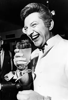 00135 Prints: Pianist Liberace drinks a soft drink at a press conference March 1968