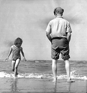 Waves Prints: The picture shows a father or grandfather with a little girl on the beach