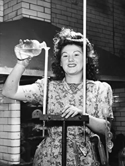Munitions Prints: Picture shows Joyce Richardson, a munitions worker. She is pouring a liquid down a
