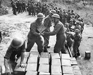 The Pioneer Corps handling tins and drums of petrol and oil using a human chain