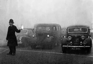 Motor Cars Prints: Policeman on point duty seen here using flares to guide the traffic during a heavy smog