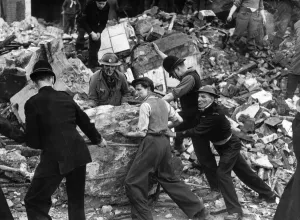 Wreckage Prints: Policeman in short sleeves helmet frantically trying to move a giant rock in the wreckage