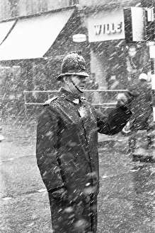 City Of London Prints: Policeman on traffic duty outside Moorgate underground station battles on through