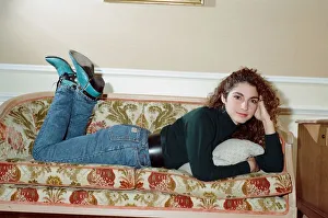 Pop singer Gloria Estefan poses lying down on a sofa in her hotel room on a visit to