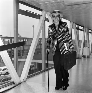 Walking Stick Prints: Pop star Elton John wearing a hat trimmed with flowers and feathers