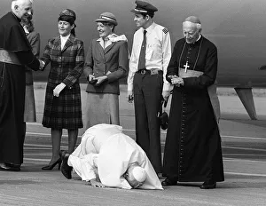 Pope John Paul II kneels down and kisses the ground at Cardiff airport on his visit to