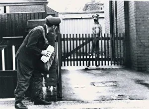 A Postman hides behind a wall scared of a Great Dane dog leaning on fence Dogs