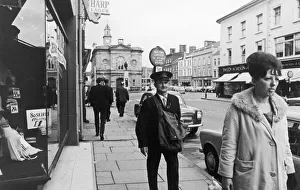 Northern Ireland Prints: Postman seen here walking through the shopping area of Coleraine after delivering all his