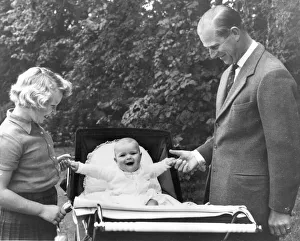 Prince Andrew laughs while sitting in his pram as he grips the finger of his father