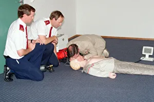 01507 Prints: Prince Charles demonstrating resuscitation techniques on an inflatable doll at an