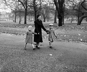 Princess Anne (4) and Prince Charles (6) walk through Green Park with their Governess