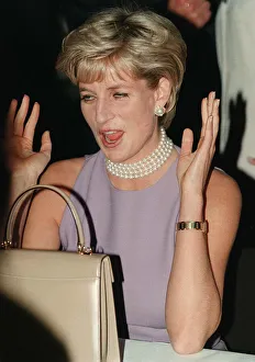PRINCESS DIANA, WEARING A PURPLE DRESS AND NECKLACE LAUGHS AT AN EVENT HELD BY