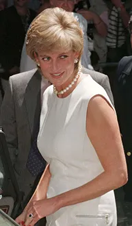 Princess Diana, wearing a white dress and necklace during a visit to a rehabilitation
