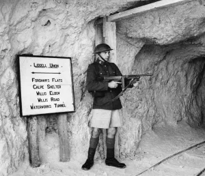 Guard Prints: A private of the Kings Regiment stands guard with a sub-machine gun at the entrance