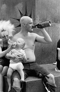 Topless Prints: Punk rocker Jock and his young son William enjoying the warm weather in Trafalgar Square