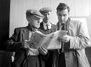 Punters studying the form guide before placing a bet at William Massey betting shop in