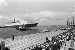 QE2 returns home to Southampton. Union Jacks are festooned on cars, draped on shoulders