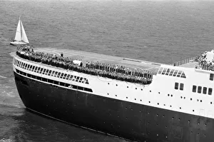 QE2 returns home to Southampton. Union Jacks are festooned on cars, draped on shoulders