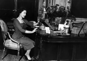Queen Elizabeth II at her desk in Buckingham Palace looking through her correspondence