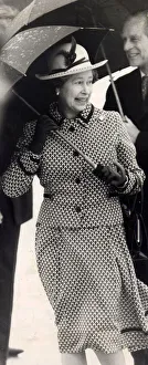 01440 Prints: Queen Elizabeth II and Prince Philip pictured with umbrellas sheltering from the rain