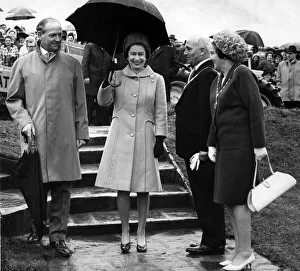 Queen Elizabeth II walks from the tree planting at Werneth Low carrying an umbrella to
