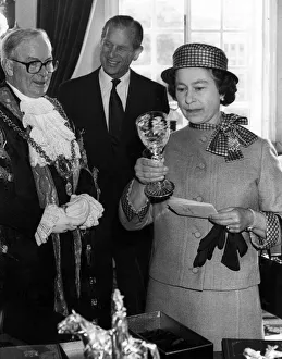 The Queen examines a Royal Doulton crystal goblet presented to her by the Lord Mayor