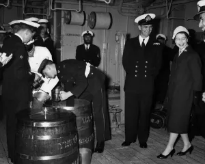 The Queen watches Officer B. R. J. Hailstone issuing the rum ration. April 1959 P009235