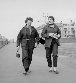 Racing drivers pat Moss and Ann Wisdom aged 21, take a brisk walk along the promenade in