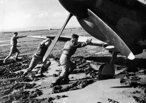 An RAF ground crew pushes a Supermarine Spitfire out of the mud on a boggy
