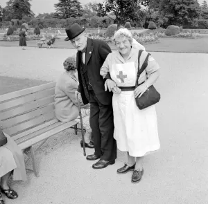 00177 Prints: A Red Cross nurse helps and elderly gentleman to a bench during a day trip to Trentham