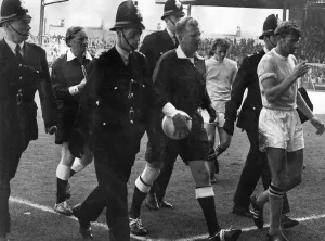 Referee David Smith gets a police escort as he leaves the Maine-road pitch following a