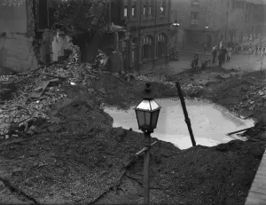 Residents gather around a water filled crater outside a public house in Newtown Row