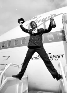 Pilot Prints: Richard Branson holding a bottle of champagne and pilots hat as he celebrates Virgin