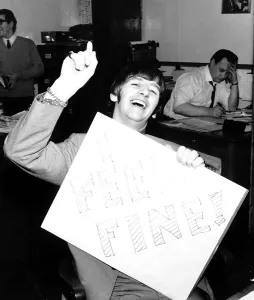 Ringo Starr drummer with the Beatles holding a placard which says I Feel Fine