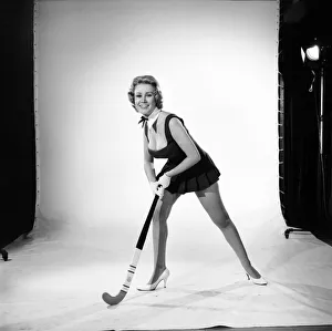 Rita Royce modelling sports kit with hockey stick. Circa 1959