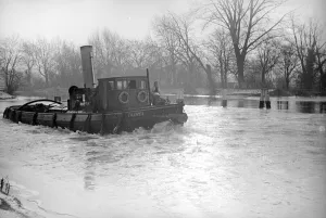 The river tug Thames makes its way through the frozen river Thames at Teddington
