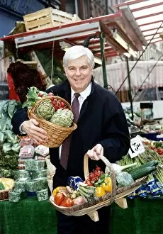 Images Dated 15th April 1994: Robert Carrier TV chef Television Standing at a fruit stall Holding baskets of
