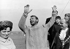 Robin Knox Jonston raises his arms in celebration as he comes ashore at Falmouth after