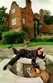Rockers Prints: Rock star Ozzy Osbourne at home Lying on a stone table with one of their pet dogs