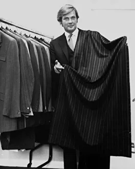 Roger Moore actor holding a length of suiting cloth October 1970 he is a director of