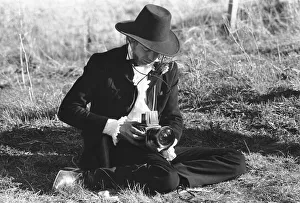 00099 Prints: Rolling Stones: Mick Jagger taking pictures with his camera as he sits on the side of