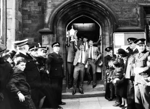 00620 Prints: Ron Tatum carries the trophy as he and the members of the team leave the town hall