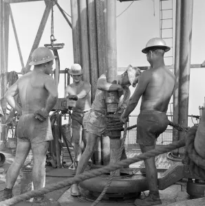 Middle East Prints: Roughnecks working on a oil production platform drilling for oil just off the coast of