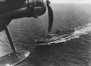 A Royal Air Force Coastal Command Sunderland flying boat flying over a transport ship